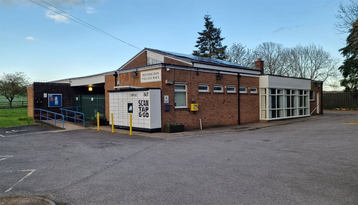 hall A brick building labelled Pittington Village Hall with a ramp, steps, and parking area.